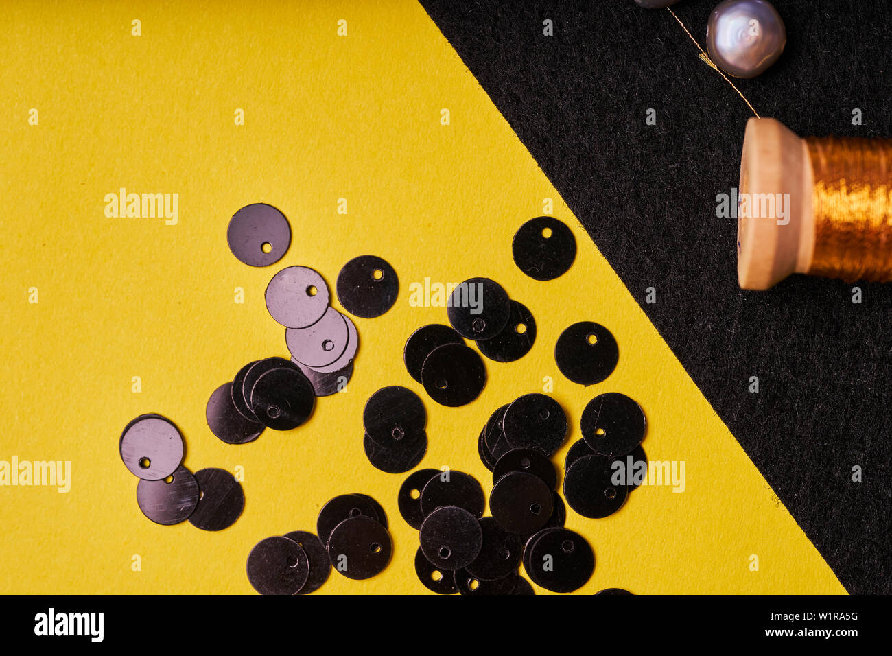 Stickerei Produkte und Werkzeuge. Spule mit Metallfaden, Perlen und Pailletten auf schwarzem Filz. Stockfoto