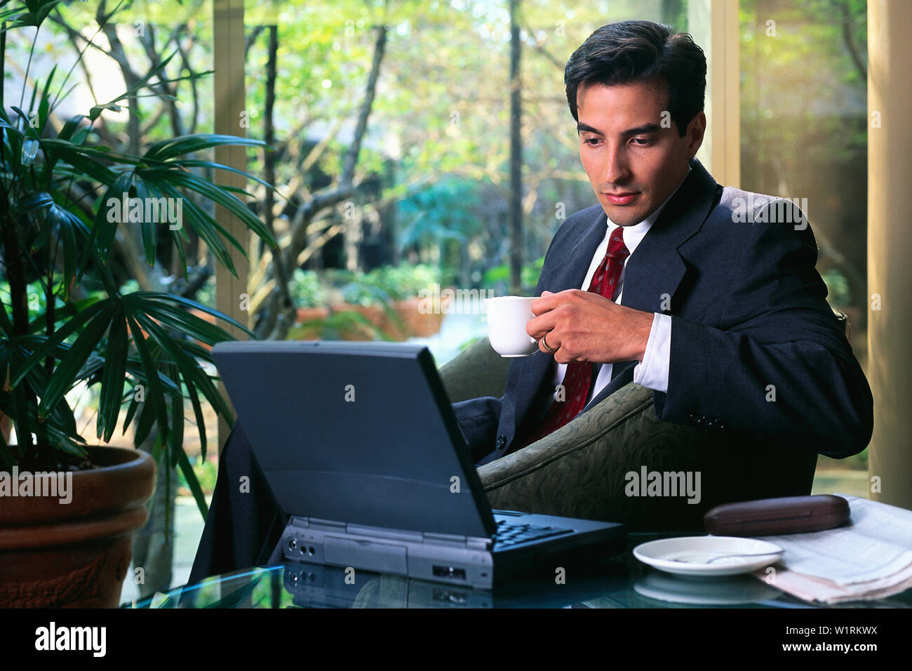 Unternehmer, die in einer Hotellobby trinken mit seinem Laptop Kaffee Stockfoto