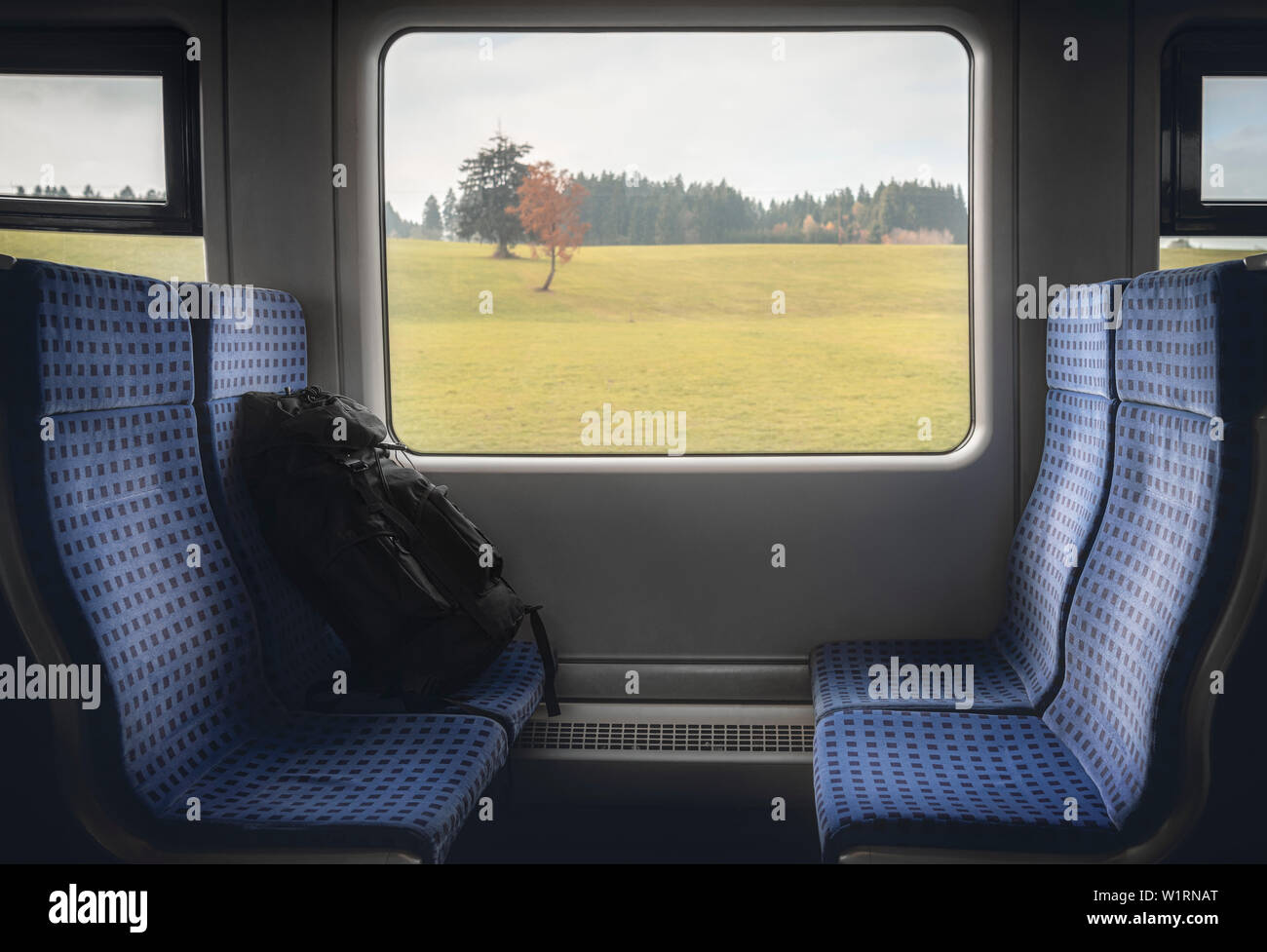 Reisen durch Deutschland Konzept Bild mit Deutschen Regionalbahn Innenraum mit blauen Stühlen, Gepäck und einen Herbst Landschaft auf dem Fenster. Stockfoto