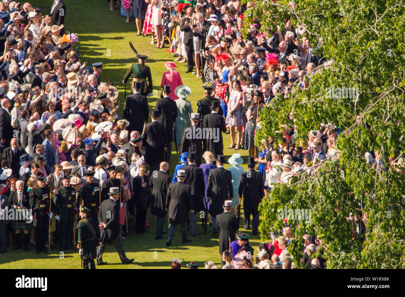 Edinburgh, Großbritannien. Vom 3. Juli 2019. Ihre Majestät die Königin (abgebildet in rosa Kleid und rosa Hut) hat ihren jährlichen Gartenparty am Palast von Holyroodhouse in Edinburgh während Royal Woche in Schottland gehostet werden. Ihrer Majestät der Königin Garden Party wurde von Menschen aus allen Schichten besucht und Gesellschaftsschichten. Die Sonne hat ein fantastisches Aussehen und die Band Musik gespielt und einige der bekannten Zahlen. Gäste genossen den Nachmittagstee mit Gourmet Sandwiches, Kuchen und Pralinen. Credit: Colin Fisher/Alamy leben Nachrichten Stockfoto