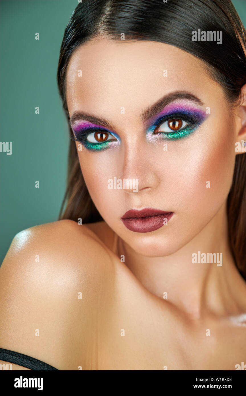 Porträt einer Mode schöne Frau mit langen Haaren und perfekte Haut in trendigen Fashion Make-up auf Smaragd Hintergrund. Auge Modelle mit bunten Glitter Stockfoto