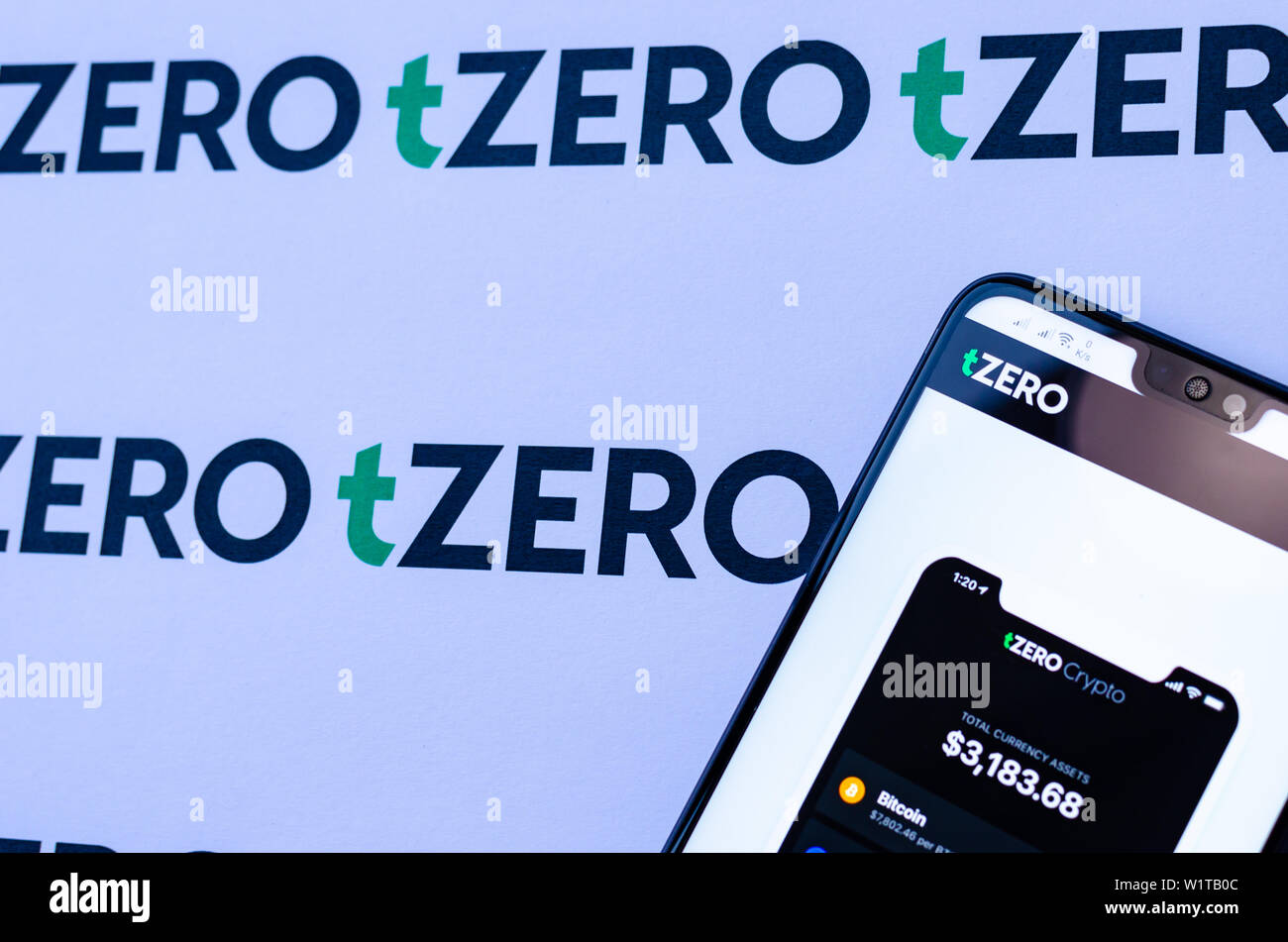 TZero Logos auf die Broschüre und das Smartphone mit dem tZERO Crypto App Screenshot. Stockfoto