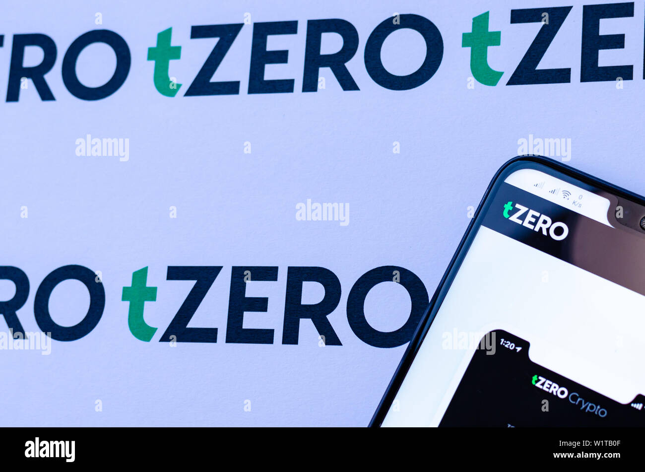 TZero Logos auf die Broschüre und das Smartphone mit dem tZERO Crypto App Screenshot. Stockfoto