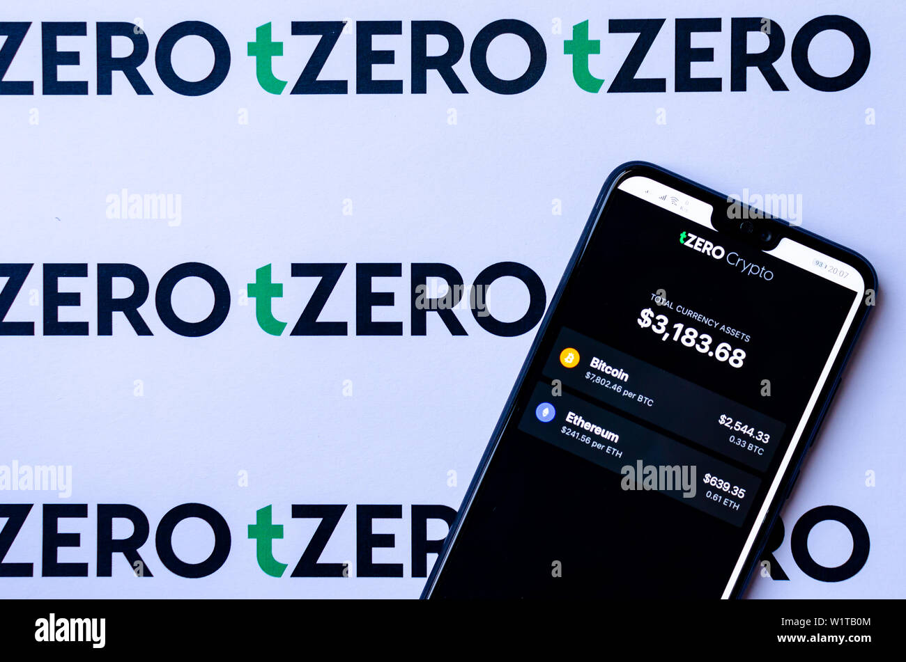 TZero Logos auf die Broschüre und das Smartphone mit dem tZERO Crypto App Screenshot. Stockfoto