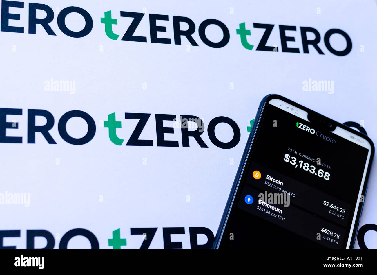 TZero Logos auf die Broschüre und das Smartphone mit dem tZERO Crypto App Screenshot. Stockfoto