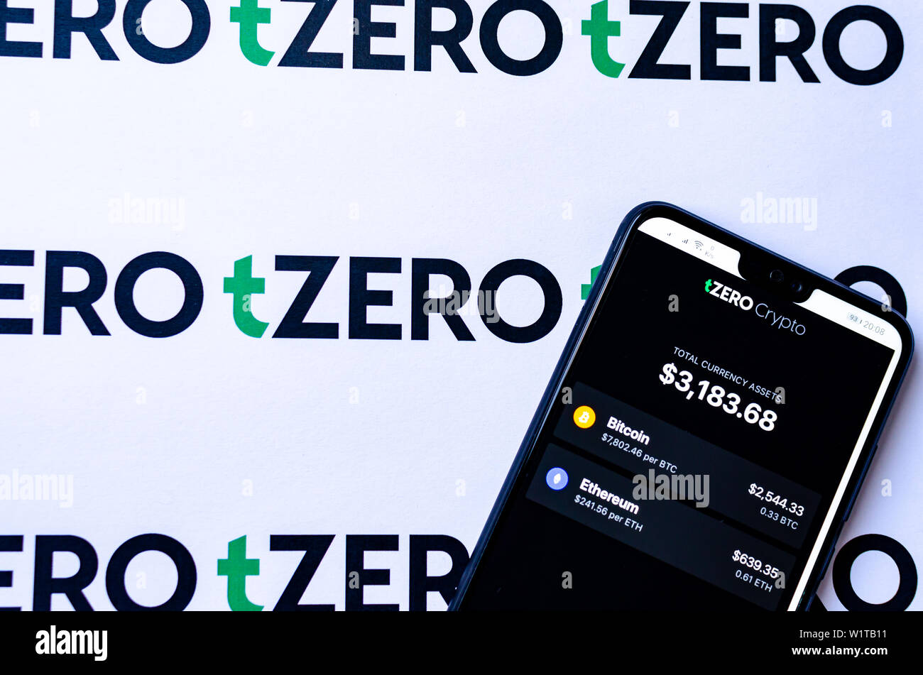 TZero Logos auf die Broschüre und das Smartphone mit dem tZERO Crypto App Screenshot. Stockfoto