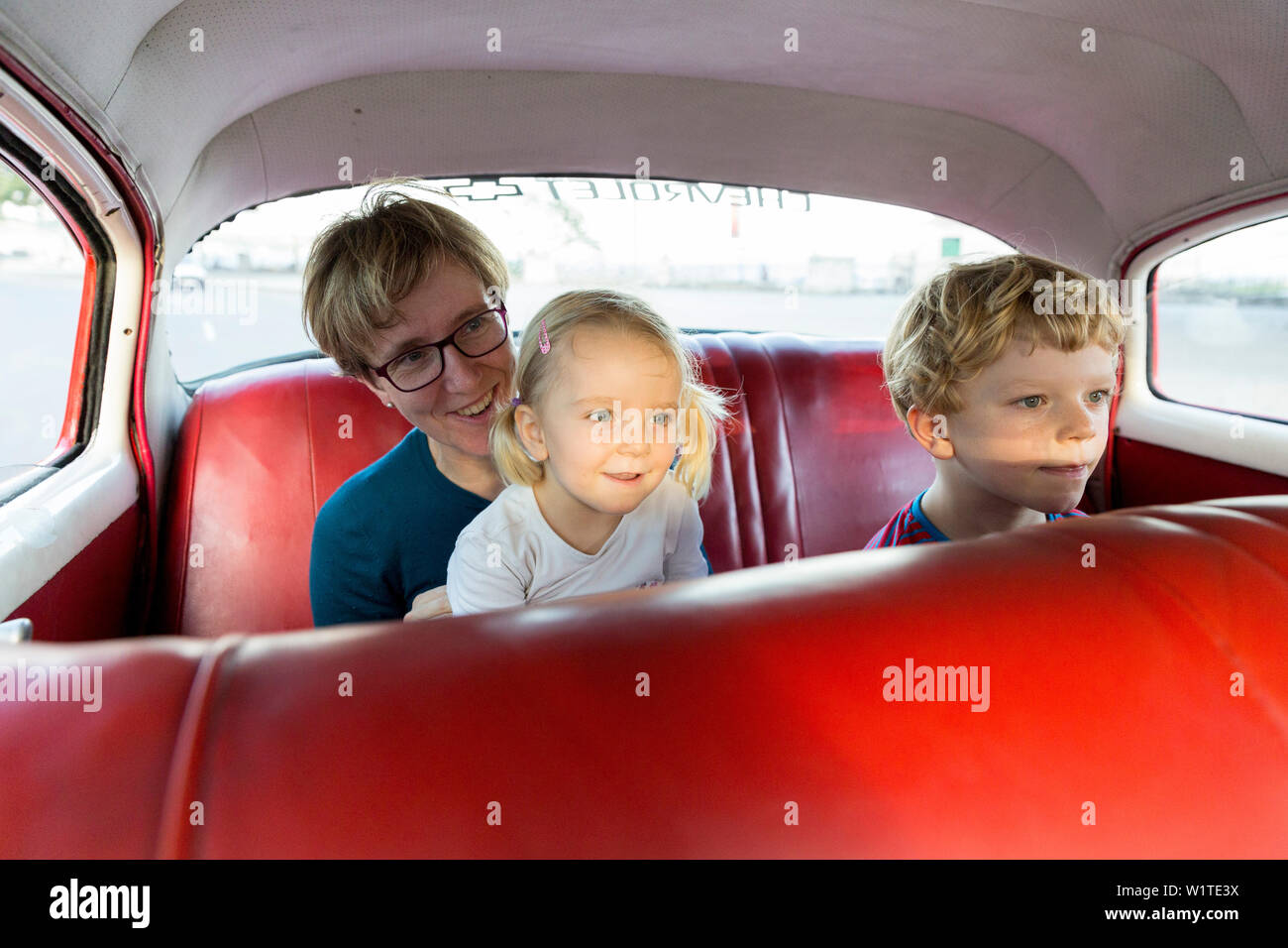 Mutter mit Kindern, sitzen in einer roten Oldtimer, komfortable Sitzgelegenheiten, Altstadt, Altstadt, Habana Vieja, Familienreisen, Reisen nach Kuba, elterliche le Stockfoto