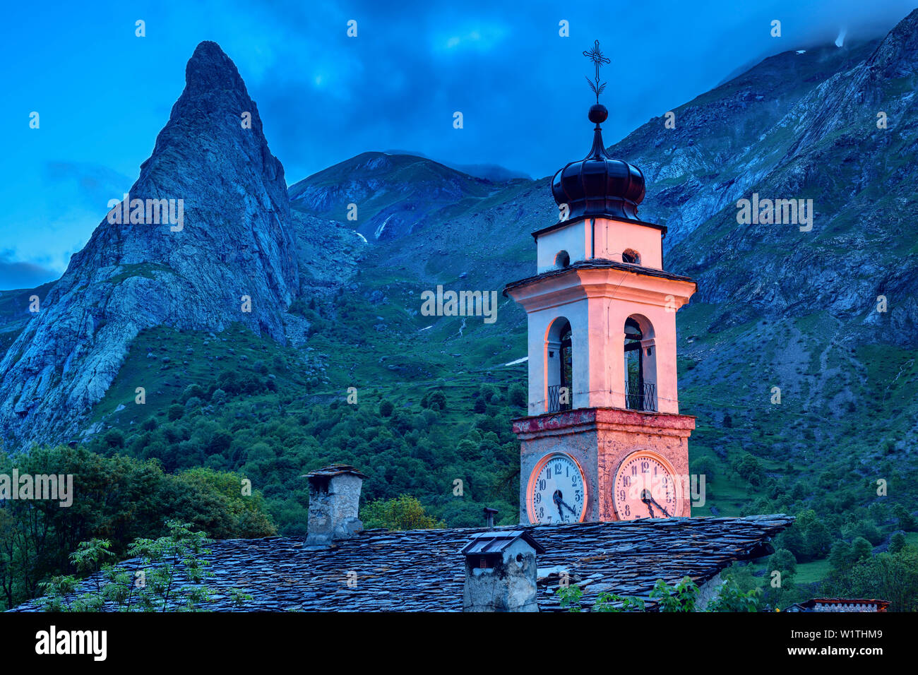Kirche von Chiappera, beleuchtet, mit Rock spire Rocca Castello im Hintergrund, Chiappera, Val Maira, Cottischen Alpen, Piemont, Italien Stockfoto