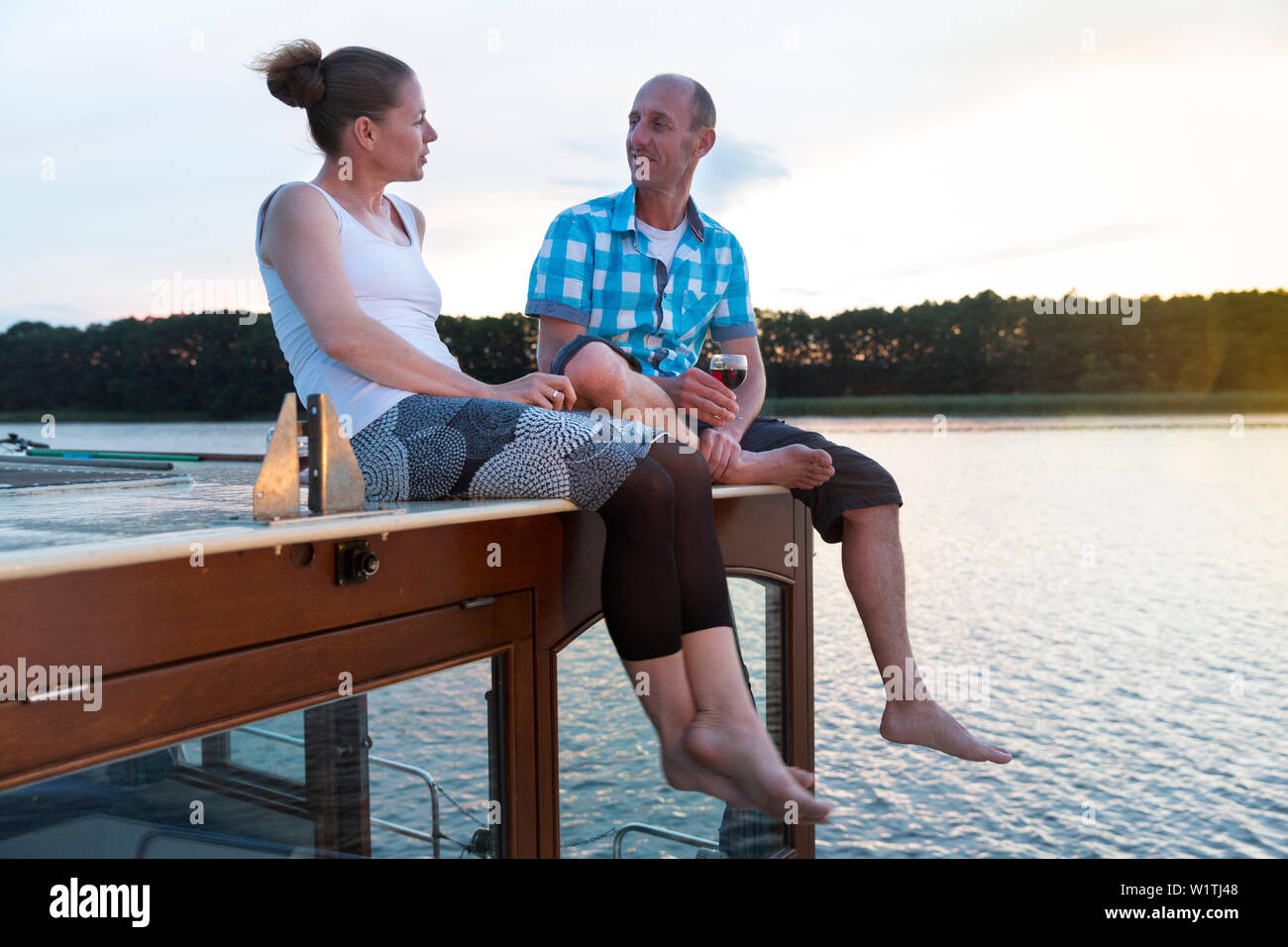 Mann und Frau, Wein trinken und auf dem Boot, Sonnenuntergang, romantisch, Hausboot tour, mirower See sehen, Kuhnle-Tours, Mecklenburgische Seenplatte, Mecklenburger Seenplatte, M Stockfoto