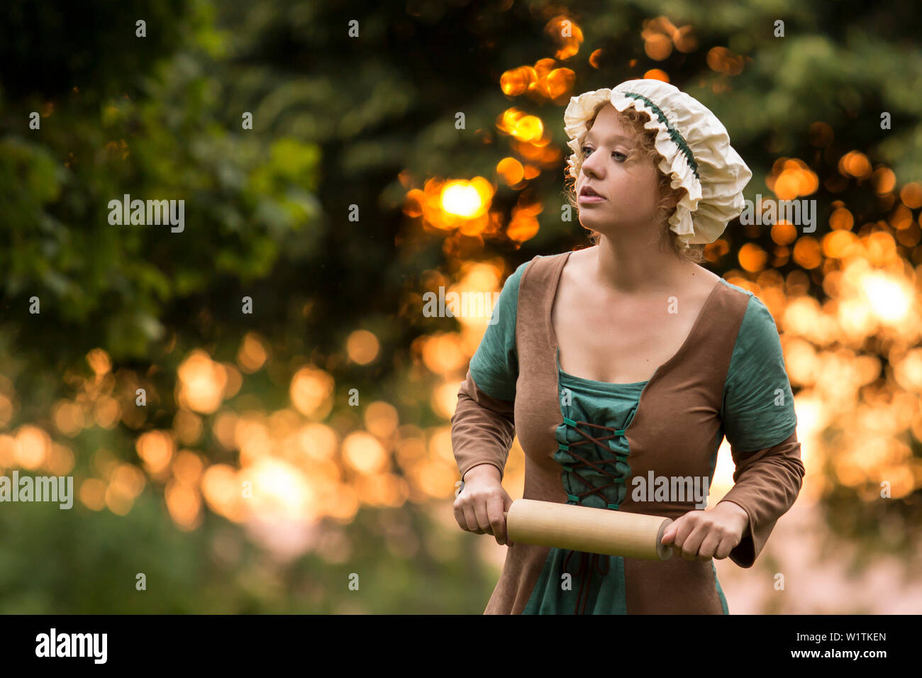 Hübsche Maid (MR) mit Rolling Pin im schwindenden Licht des Sonnenuntergangs auf dem Burgberg Frankenberg (Eder), Hessen, Deutschland, Europa Stockfoto