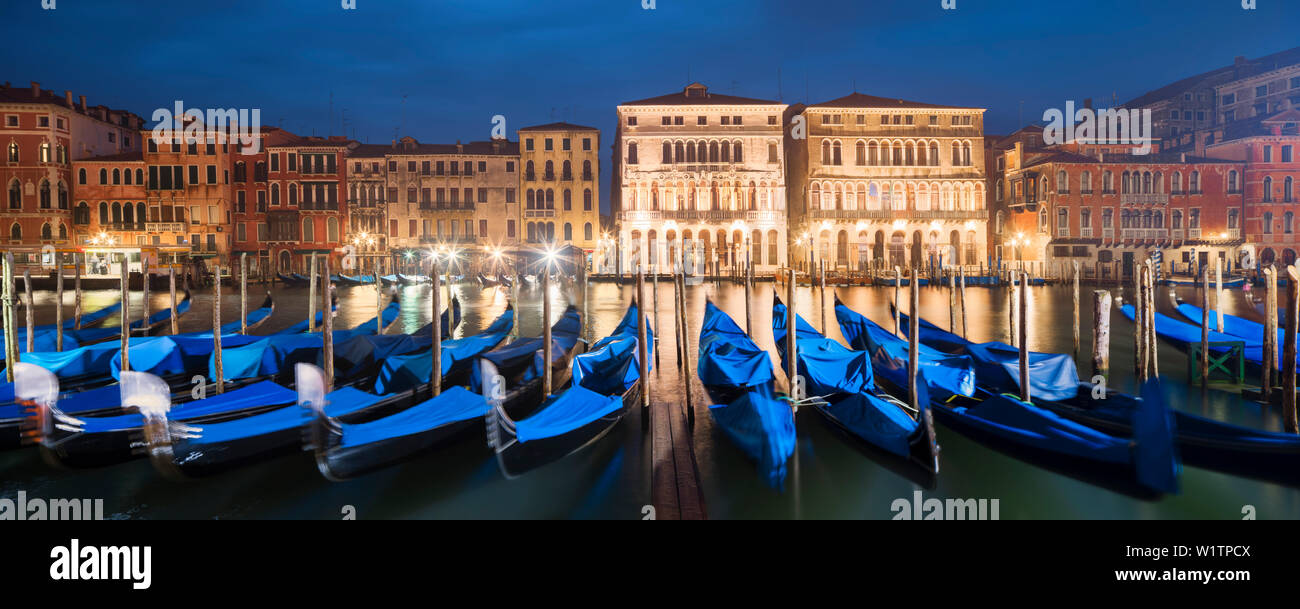 Panorama mit Blick auf den Canal Grande mit der beleuchteten Fassaden der Palazzo Ca' Loredan und Palazzo Ca' Farsetti (von links) in der Blauen Nacht und gondol Stockfoto