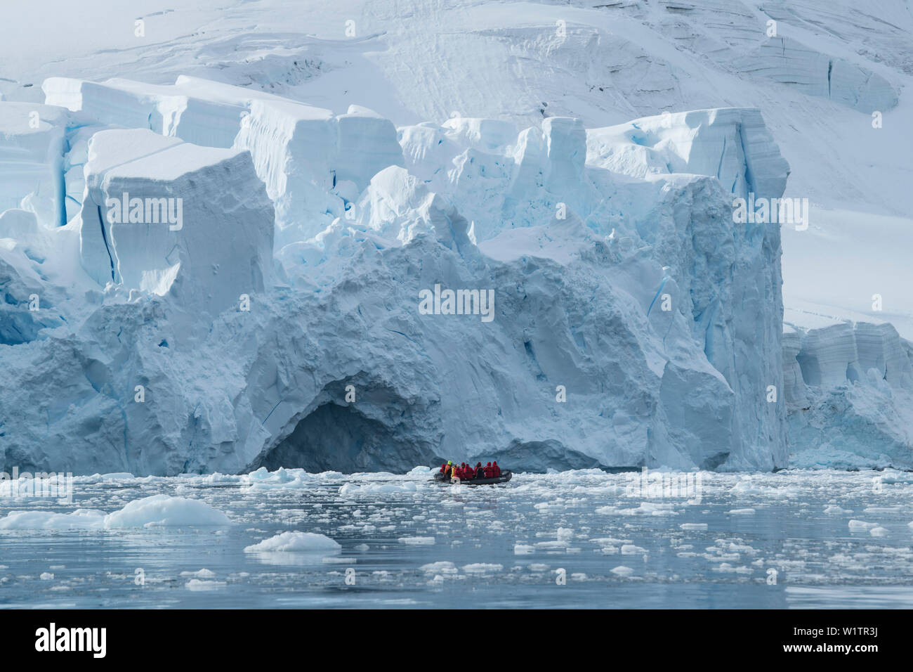 Ein Zodiac Beiboot floss mit Passagieren Kreuzfahrten durch schwimmende Eis vor einem massiven Gletscher vorne, Paradise Bay (Paradise Harbour), Danco Coast, Gr Stockfoto