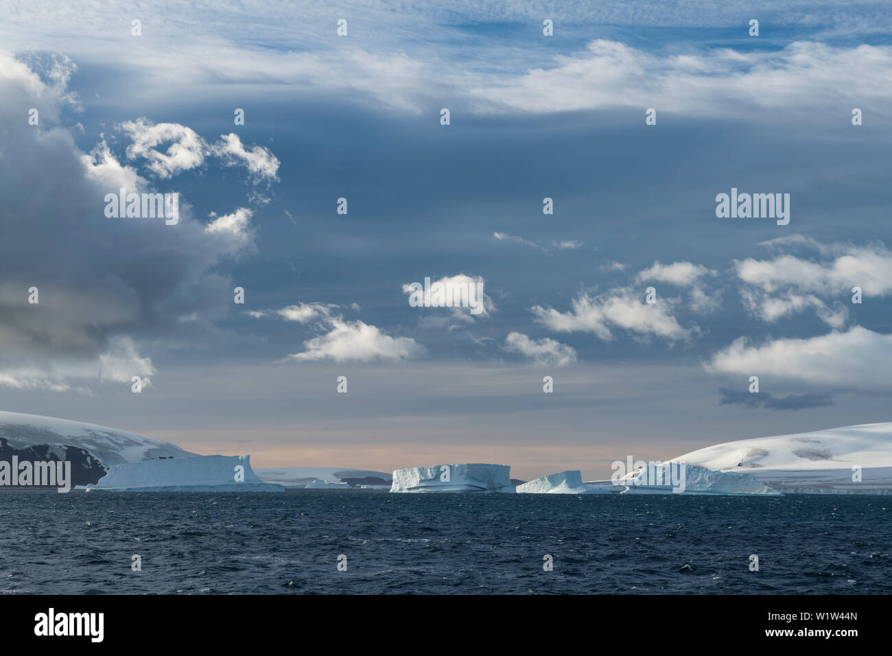Dramatischen Licht verwandelt eine Szene mit Schnee - Inseln, Eisberge und wispy Wolken in einer verträumten Landschaft bedeckt, Brown Bluff, Weddellmeer, Antarktis, Pe Stockfoto