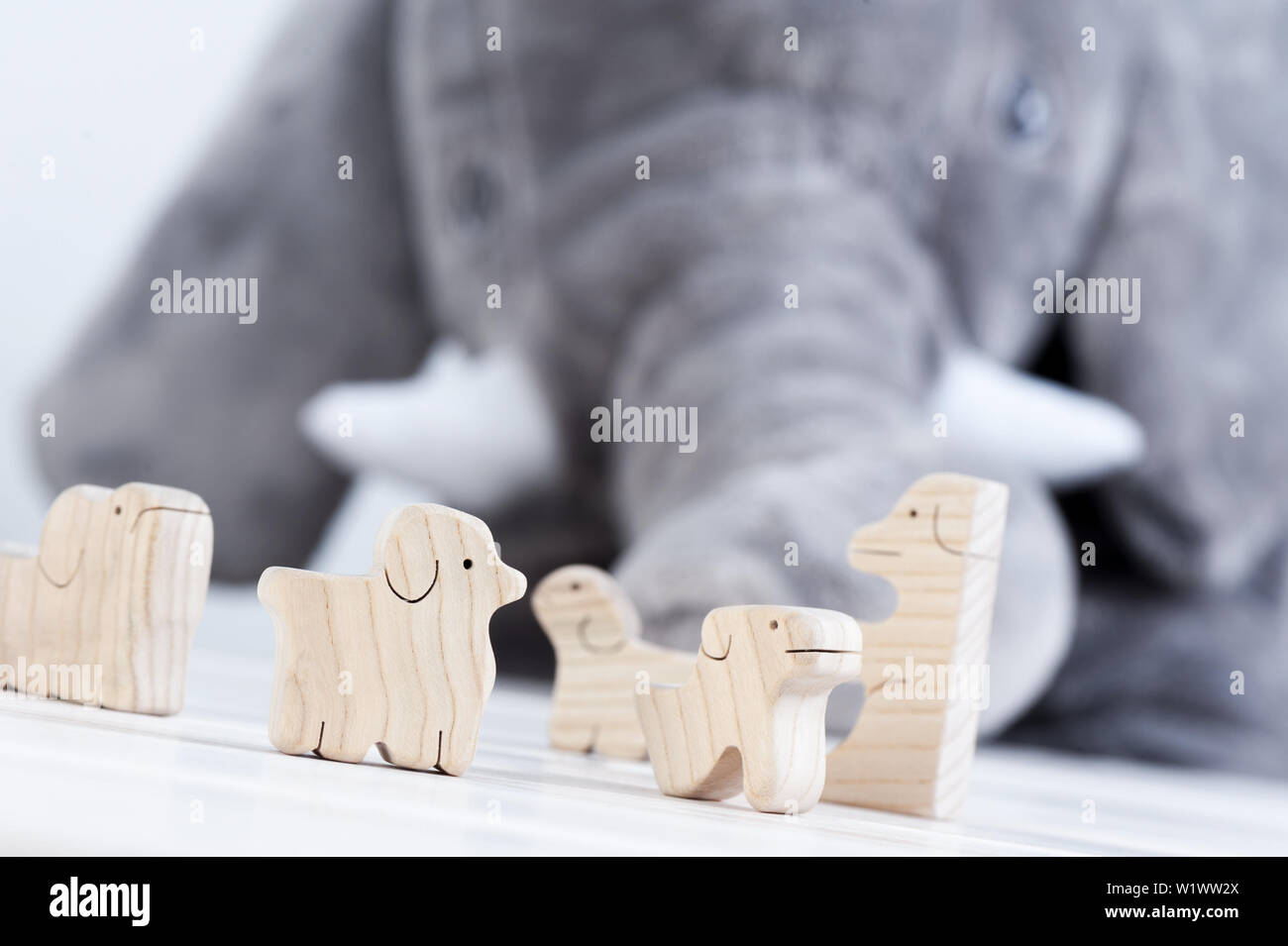 Cute Holzspielzeug Tiere auf weißem Holz Plank mit riesigen Elefanten Puppe im Hintergrund Stockfoto