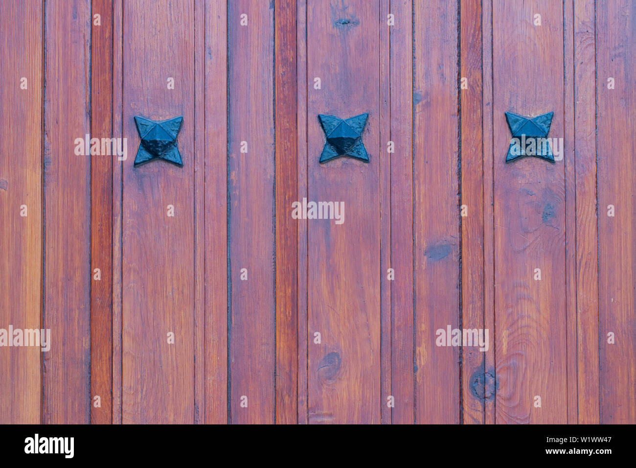 Holz Textur Hintergrund. Nahaufnahme eines Details aus Holz rot braun Eingangstür mit drei Metall Sterne auf der hölzernen Planken. Makro. Stockfoto