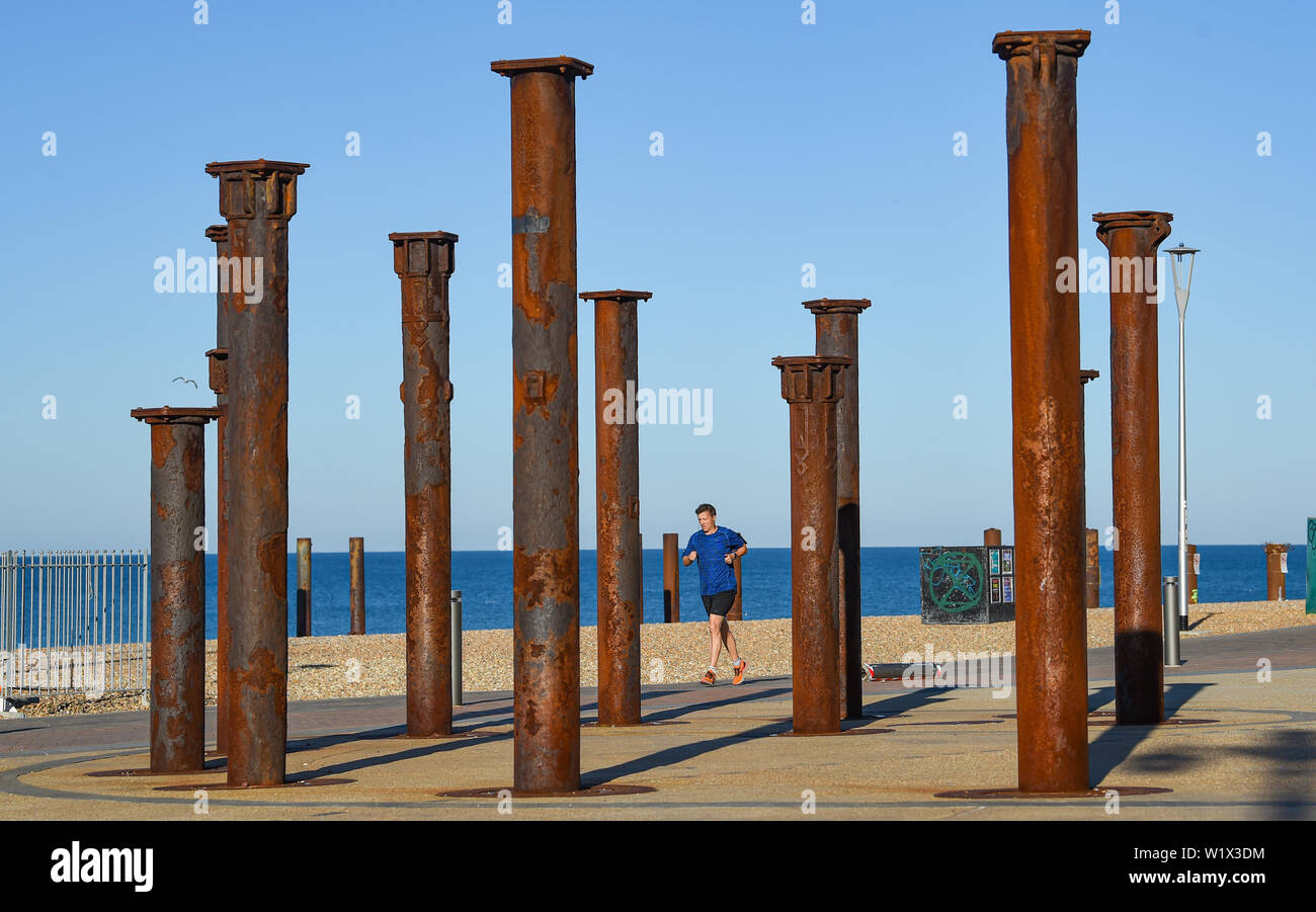 Brighton UK 4. Juli 2019 - ein Läufer geniesst die Sonne am frühen Morgen, als er durch die Goldene Spirale Art Installation auf Brighton Seafront. Das Wetter wird prognostiziert einen weiteren sonnigen Tag an der Südküste von Großbritannien mit zu erwartenden Höchsttemperaturen um 27 Grad in einigen Teilen zu erreichen. Foto: Simon Dack/Alamy leben Nachrichten Stockfoto