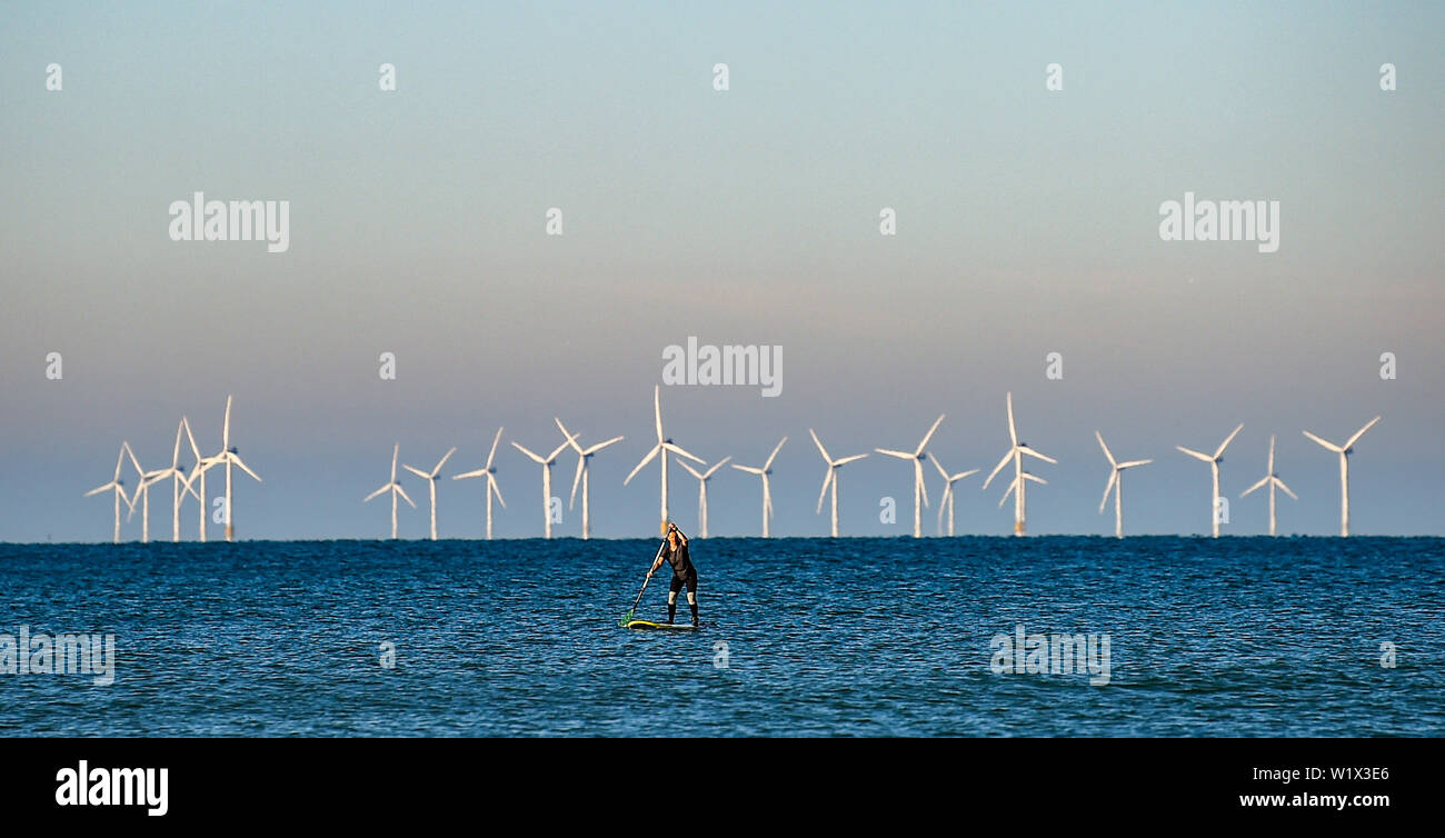 Brighton UK 4. Juli 2019 - ein Paddel boarder geniesst die Sonne am frühen Morgen aus Brighton Beach mit den Rapunzeln Wind Farm hinter in der Ferne. Das Wetter wird prognostiziert einen weiteren sonnigen Tag an der Südküste von Großbritannien mit zu erwartenden Höchsttemperaturen um 27 Grad in einigen Teilen zu erreichen. Foto: Simon Dack/Alamy leben Nachrichten Stockfoto