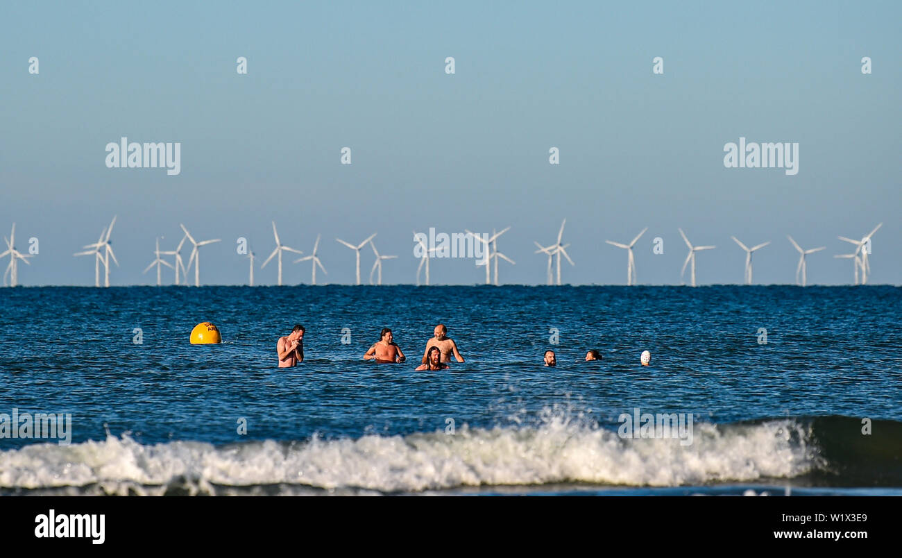 Brighton UK 4. Juli 2019 - Am frühen Morgen Schwimmer tauchen Sie ein in das Meer aus Brighton Beach mit den Rapunzeln Wind Farm hinter in der Ferne genießen. Das Wetter wird prognostiziert einen weiteren sonnigen Tag an der Südküste von Großbritannien mit zu erwartenden Höchsttemperaturen um 27 Grad in einigen Teilen zu erreichen. Foto: Simon Dack/Alamy leben Nachrichten Stockfoto