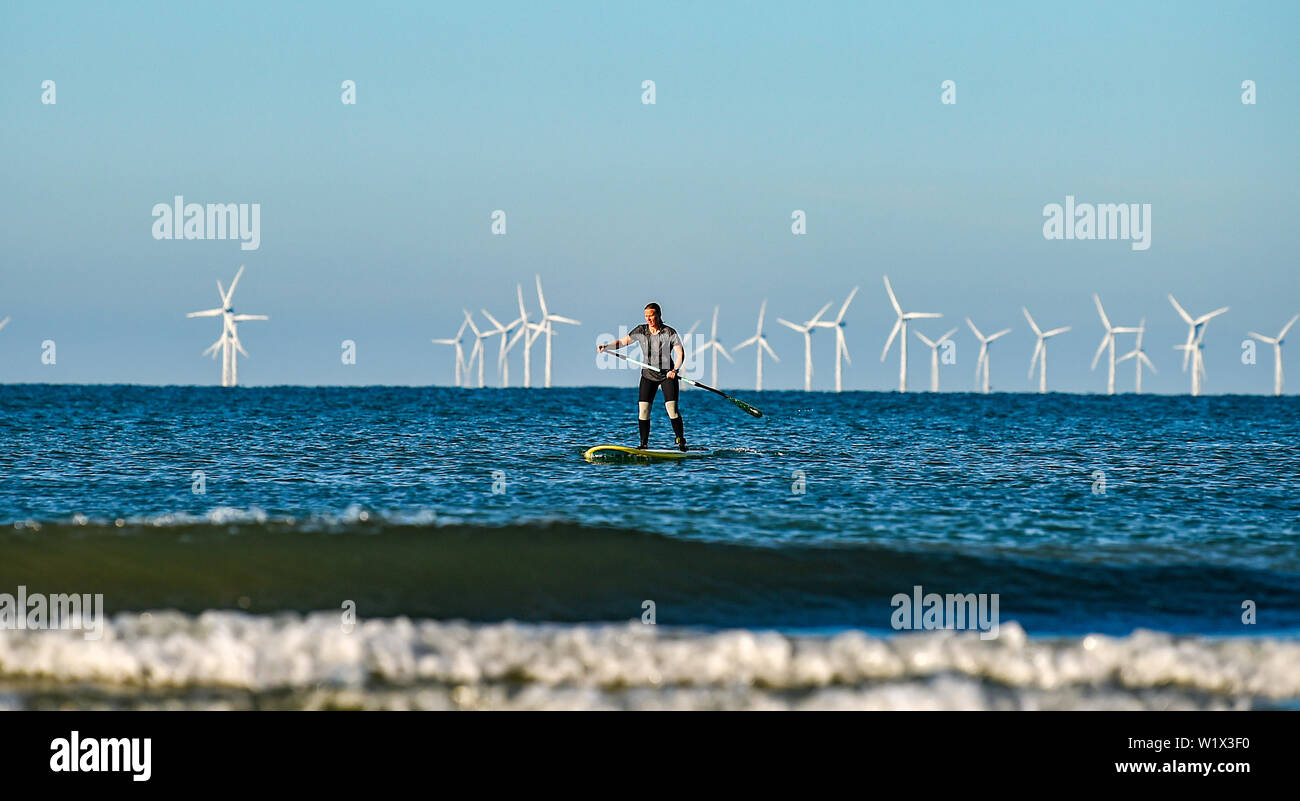 Brighton UK 4. Juli 2019 - ein Paddel boarder geniesst die Sonne am frühen Morgen aus Brighton Beach mit den Rapunzeln Wind Farm hinter in der Ferne. Das Wetter wird prognostiziert einen weiteren sonnigen Tag an der Südküste von Großbritannien mit zu erwartenden Höchsttemperaturen um 27 Grad in einigen Teilen zu erreichen. Foto: Simon Dack/Alamy leben Nachrichten Stockfoto
