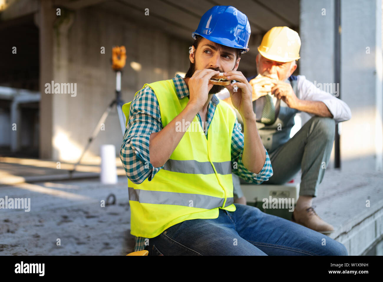 Glückliche junge und Senior Engineer Arbeiter an der Baustelle in der Pause sitzen Stockfoto