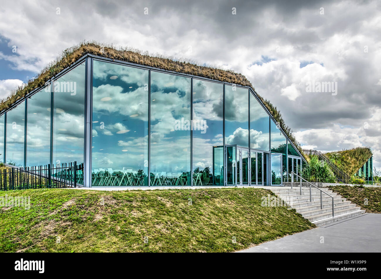 Werkendam, Niederlande, 3. Juli 2019: Himmel mit spektakulären Wolken in der Fassade des Museum Restaurant in Biesbosch Nationalpark widerspiegelt Stockfoto