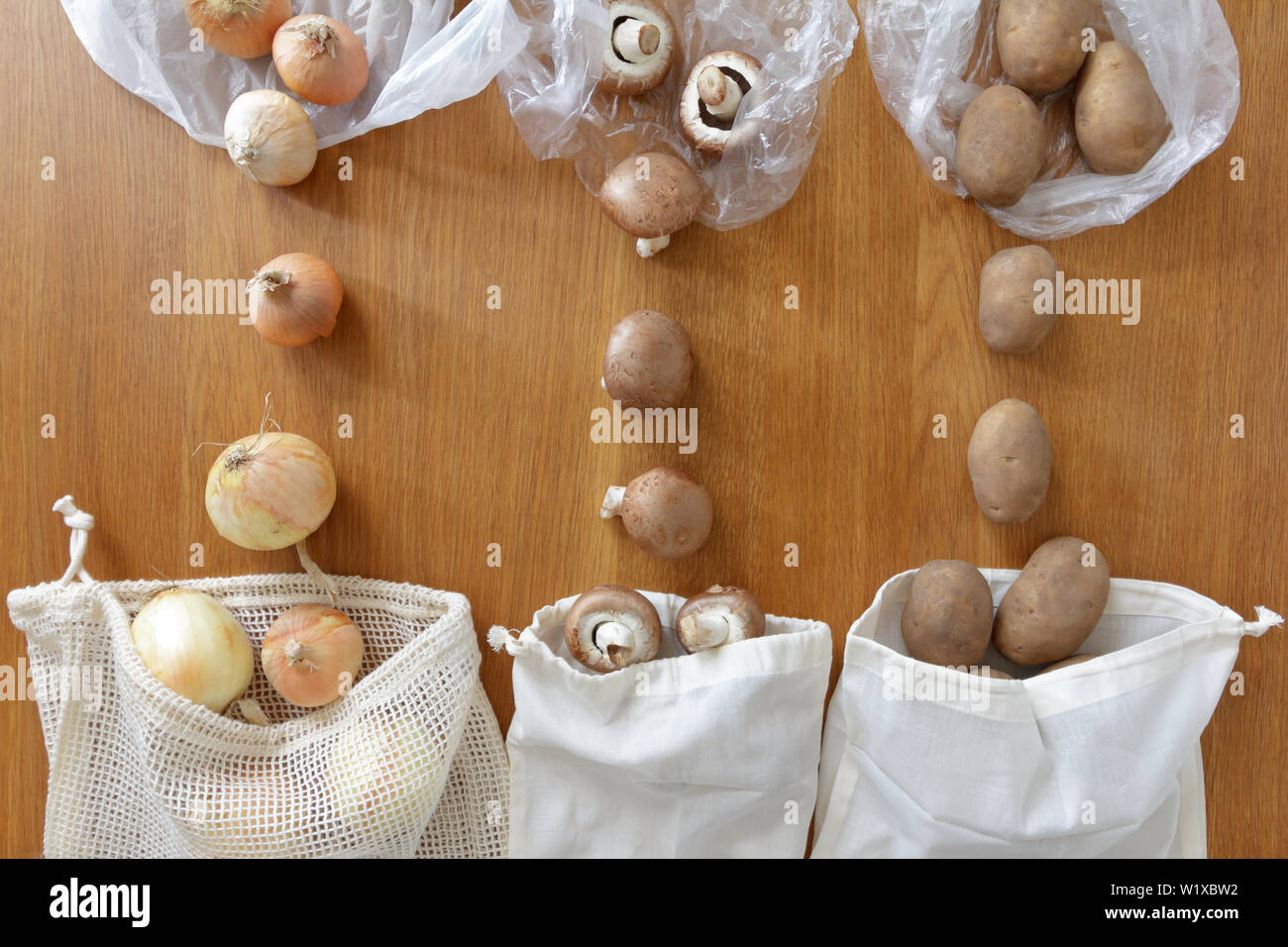 Dünne Kunststoff vs wiederverwendbare Baumwoll Einkaufstaschen mit frischen Produkten auf hölzernen Hintergrund, null Abfall Konzept. Stockfoto