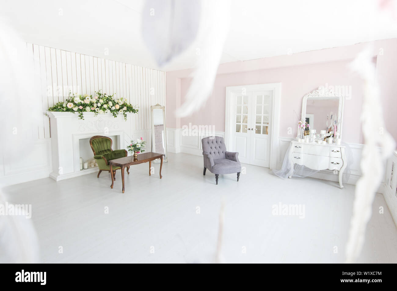 Helle luxuriöse Interieur der Wohnzimmer mit Kamin und Sesseln mit Blumen geschmückt. Stockfoto