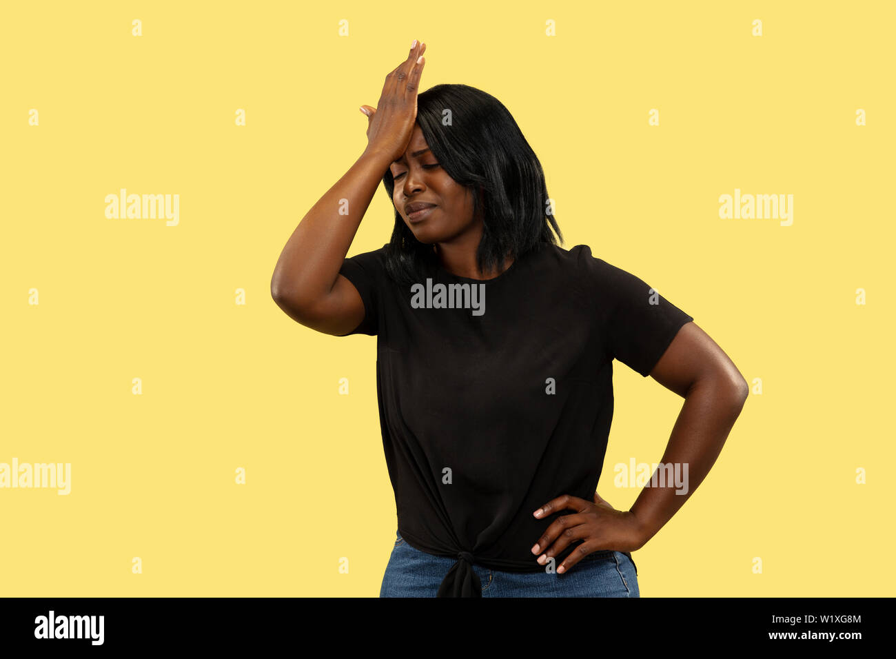 Junge Afrikanische - amerikanische Frau auf Gelb studio Hintergrund isoliert, Mimik. Schöne weibliche Brustbild. Konzept der menschlichen Gefühle, Mimik. Betrübt und schmerzte. Stockfoto