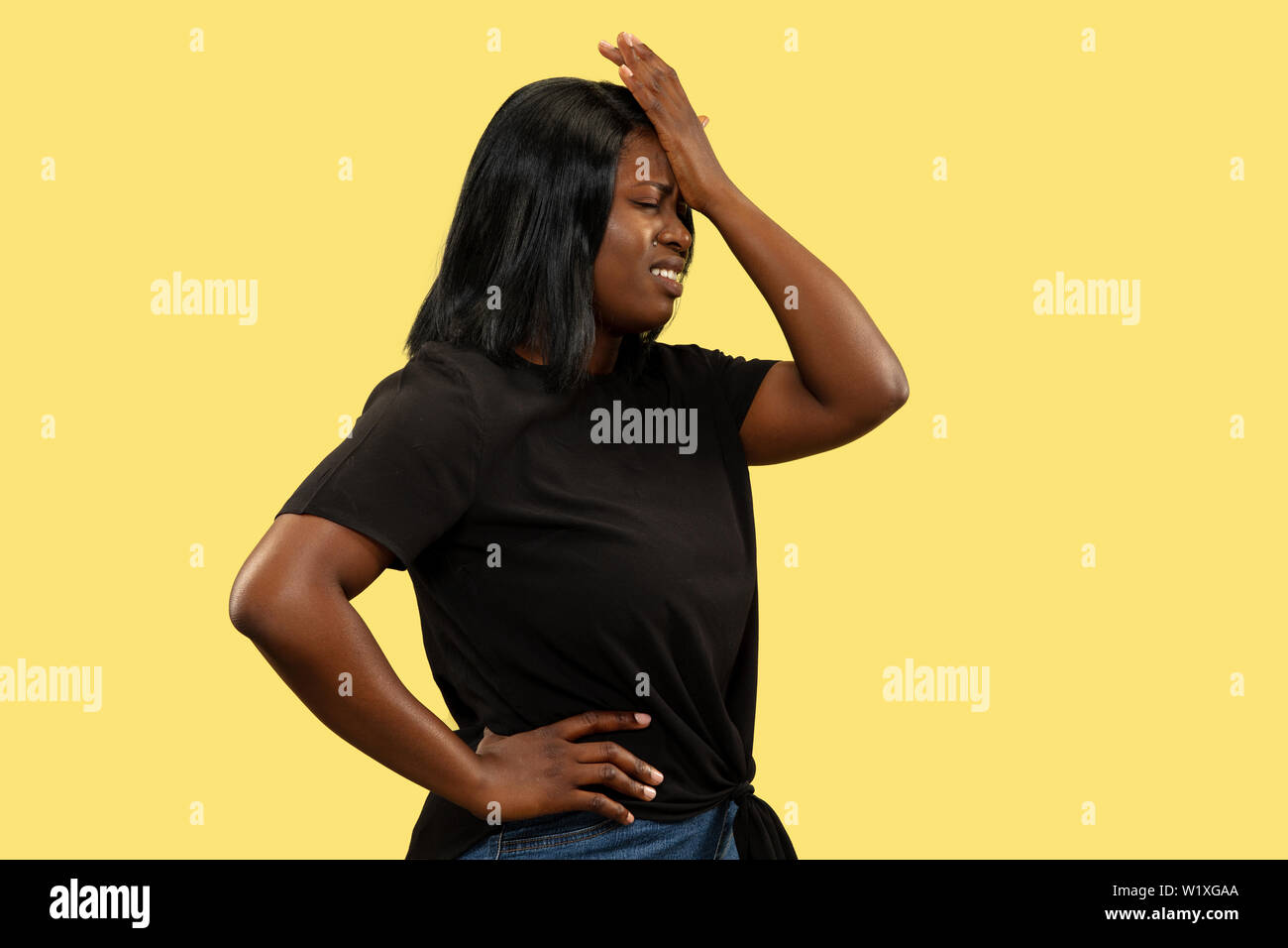 Junge Afrikanische - amerikanische Frau auf Gelb studio Hintergrund isoliert, Mimik. Schöne weibliche Brustbild. Konzept der menschlichen Gefühle, Mimik. Betrübt und schmerzte. Stockfoto