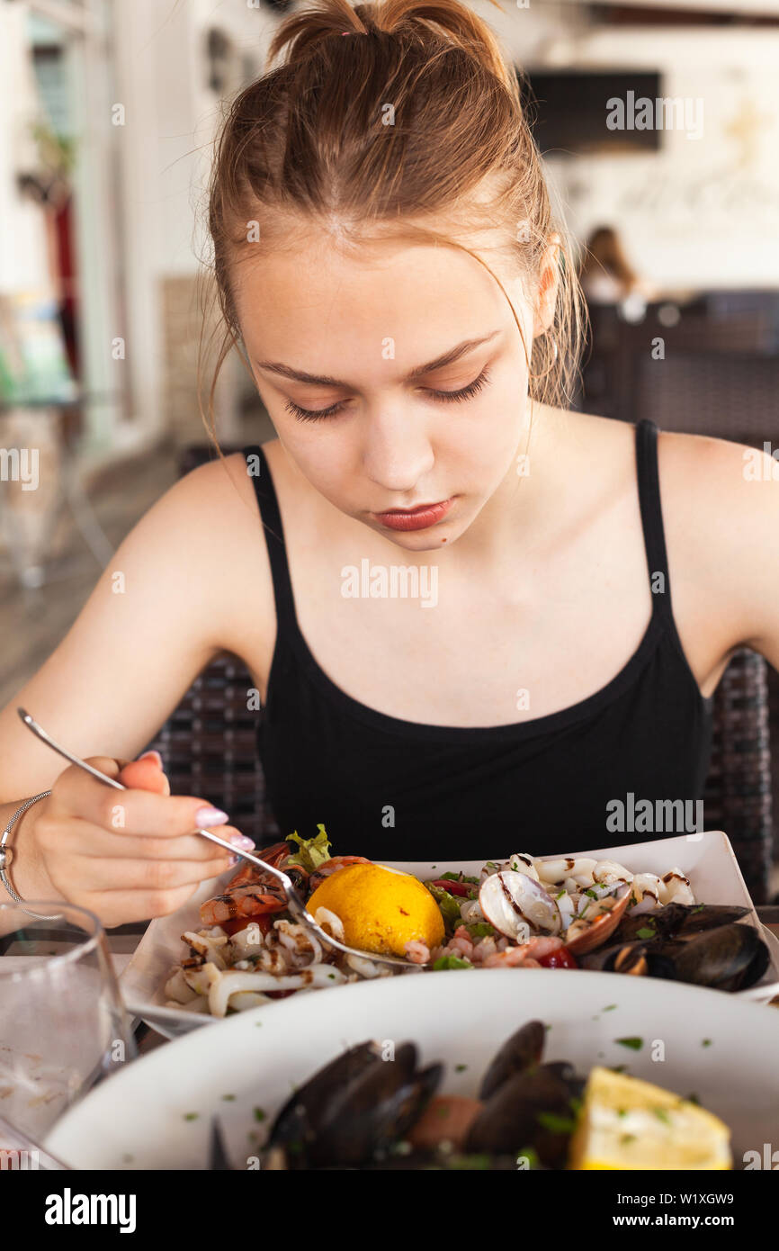 Junge schöne Blondine kaukasische Mädchen mit gemischten Salat mit Meeresfrüchten in einem mediterranen Restaurant Stockfoto