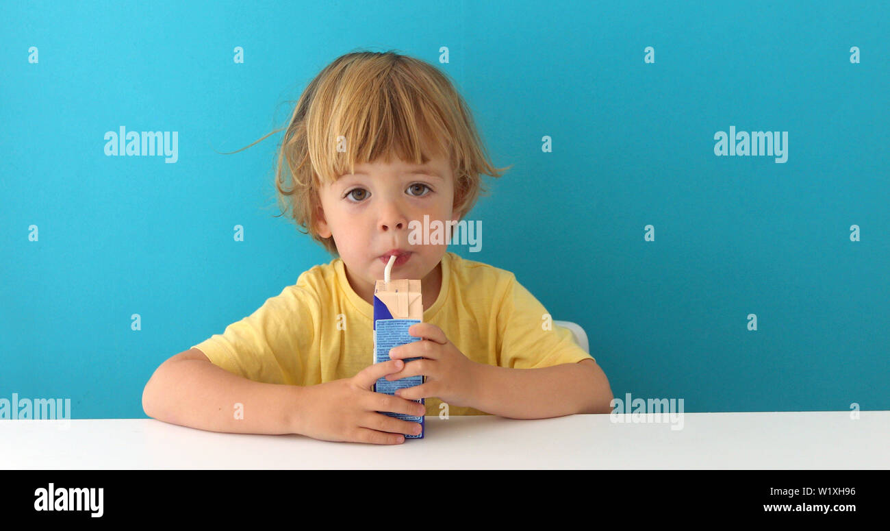 Adorable Kind trinken aus Kasten durch Stroh Stockfoto