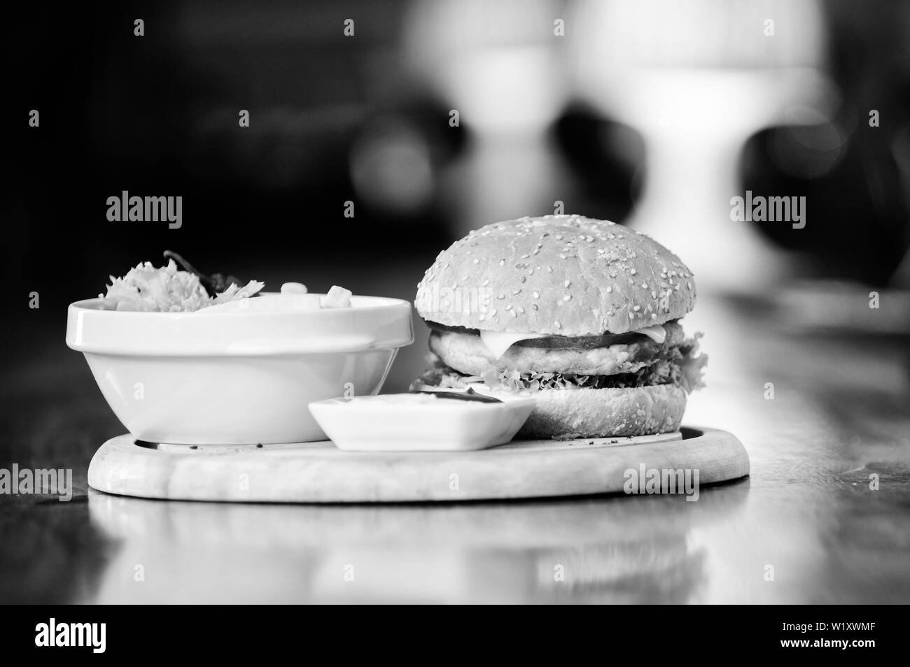 Kalorienreiche Snacks. Hamburger und Pommes frites und Tomatensauce auf Holzbrett. Fast food Konzept. Burger mit Käse, Fleisch und Salat. Cheat meal. Leckere Burger mit Sesam. Burger Menü. Stockfoto