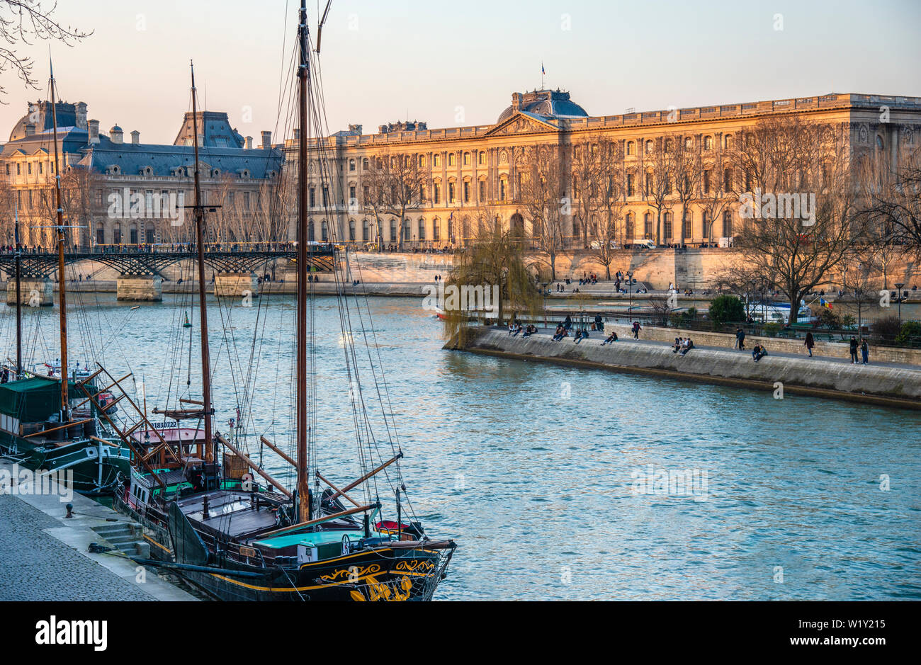 Blick auf den Louvre und dem Palast von den Ufern der Seine gelegen mit Segelschiffen in den Vordergrund mit dem Nachmittag Licht. Stockfoto