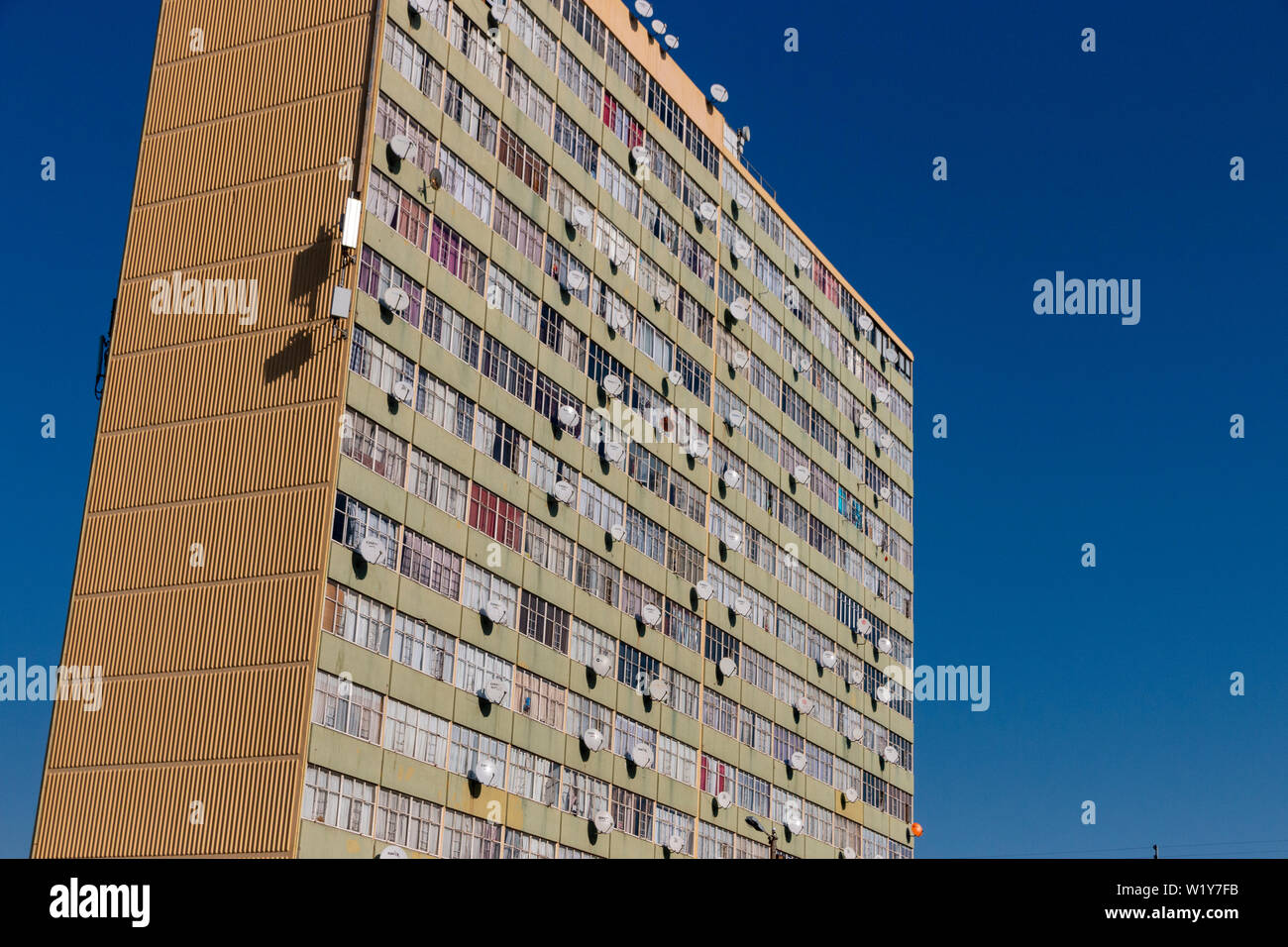 Ein Gebäude in Durban - SÜDAFRIKA - JUNI 2019 mit Satellitenschüsseln auf fast jedem Fenster mit den blauen Himmel hinter sich Stockfoto