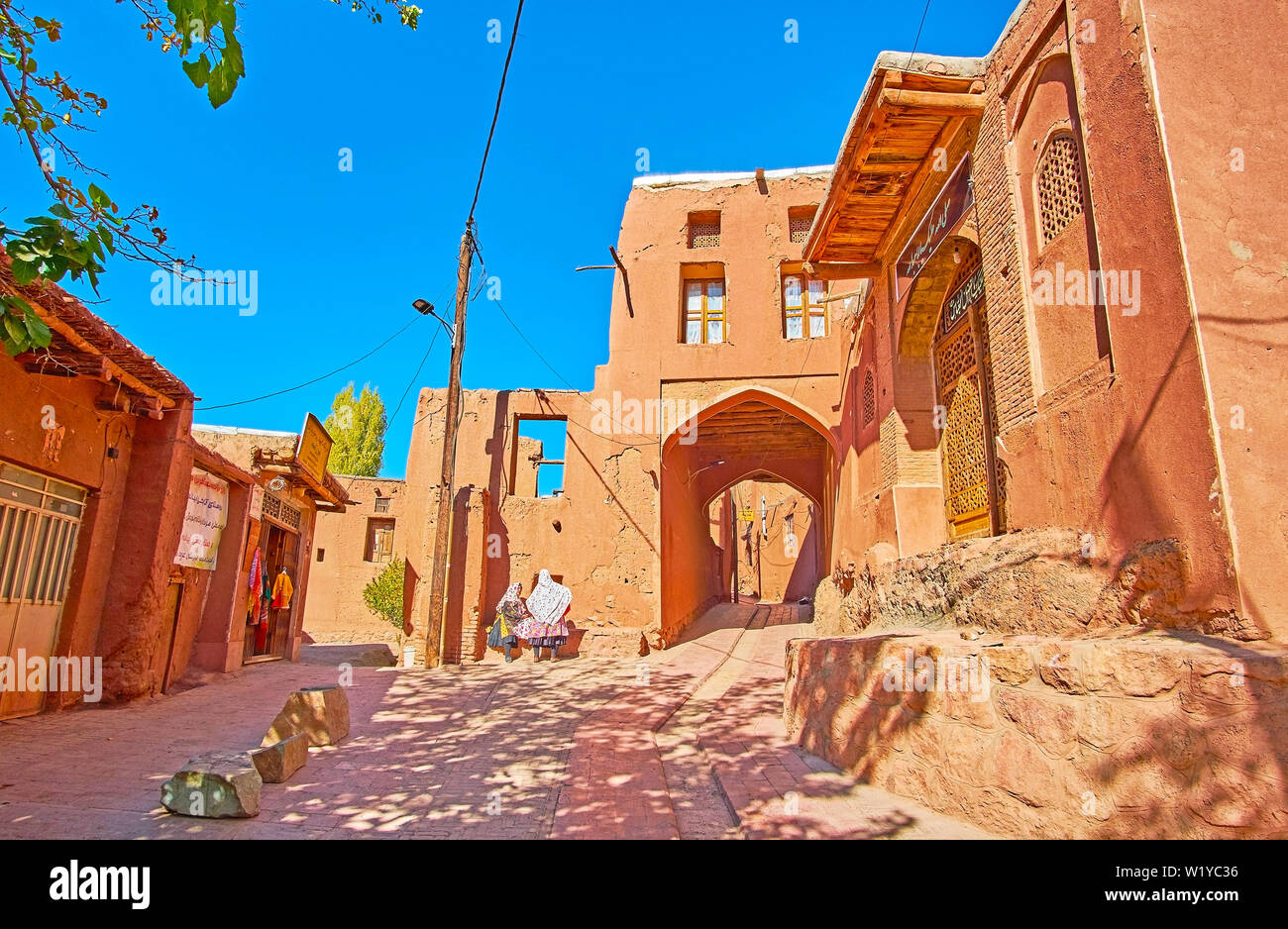 ABYANEH, IRAN - Oktober 23, 2018: zwei Abyanaki Frauen in traditioneller Kleidung sprechen in Dorf Straße neben dem touristischen Store, am 23. Oktober in Abyaneh Stockfoto