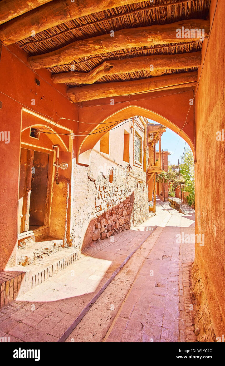 Ein Spaziergang durch die engen Pass unter dem Haus mit alten Decke und roten Adobe Wände anmelden, Dorf Abyaneh, Iran. Stockfoto