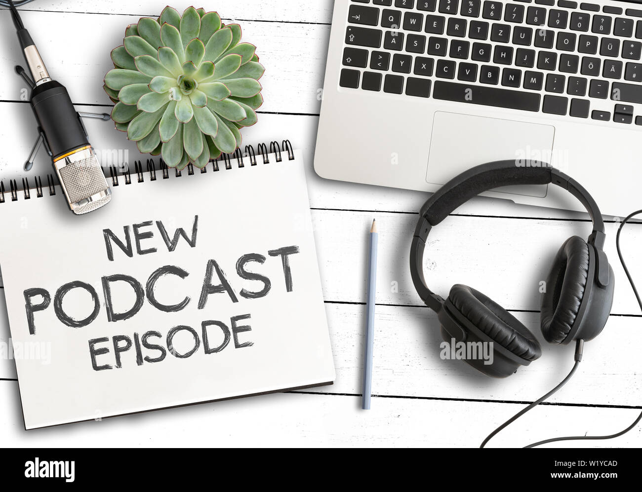 Ansicht von oben Text neuer Podcast Episode auf Notepad mit Laptop, Topfpflanzen und Recording Mikrofon auf weiße Holztisch, podcasting Konzept Stockfoto