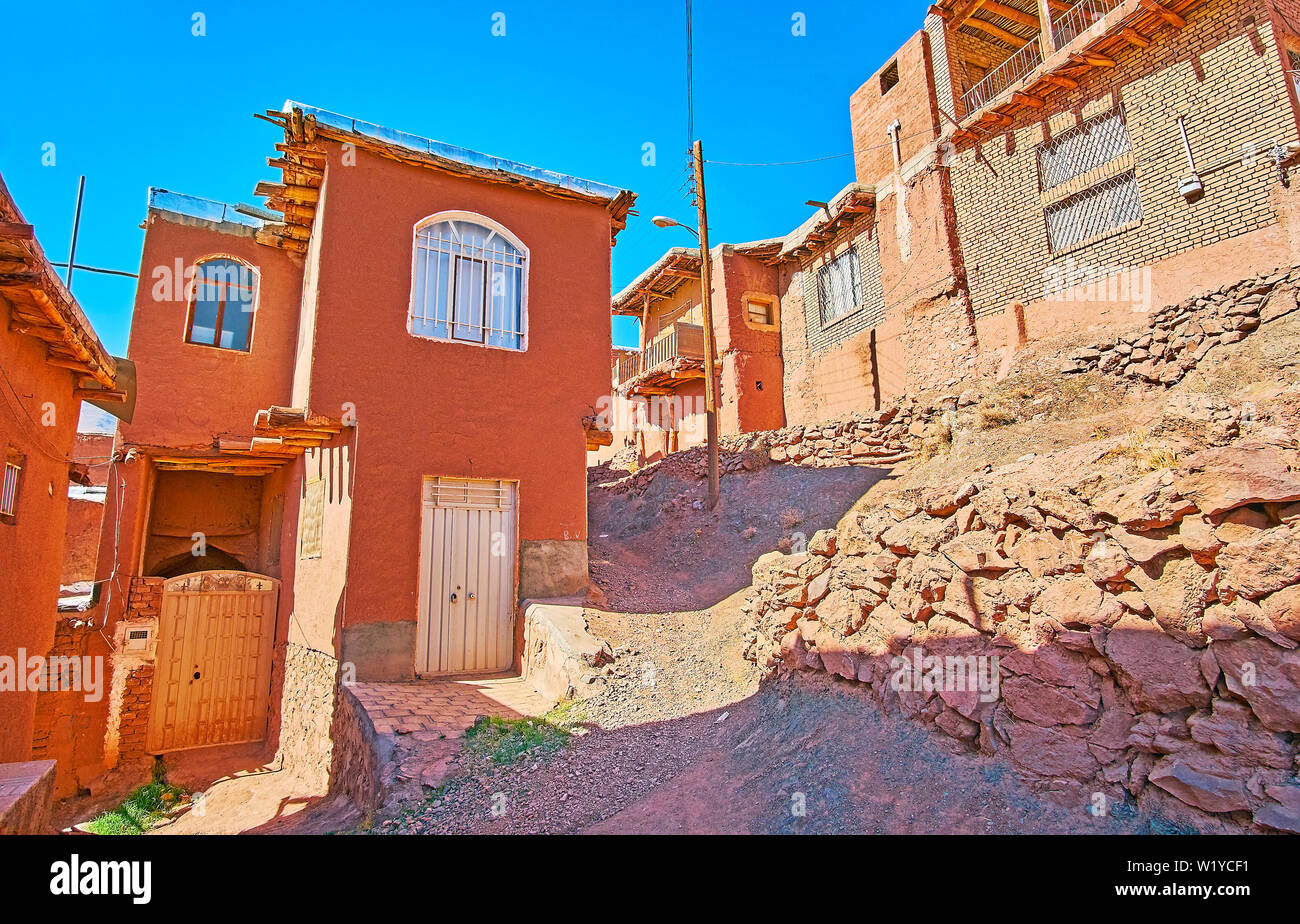 Gehen Sie die hügeligen Straßen von Abyaneh zwischen den historischen Rot-ockerfarbenen Häuser der ältesten Iranischen Dorf. Stockfoto