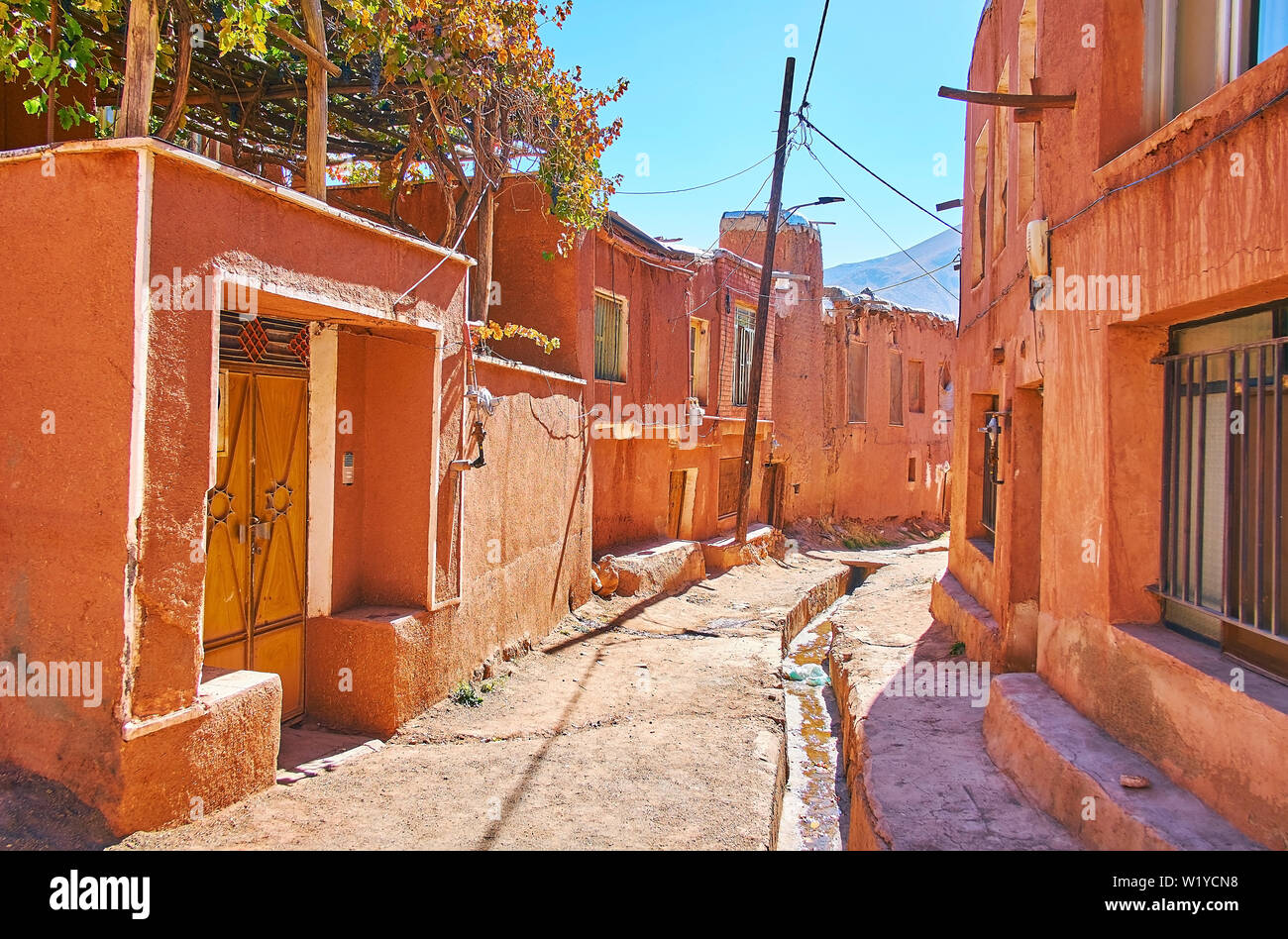 Die alte Straße von Abyaneh Dorf mit tiefen Rinne in irdenen Straße und erhaltene rötlichen Gebäude, Iran. Stockfoto