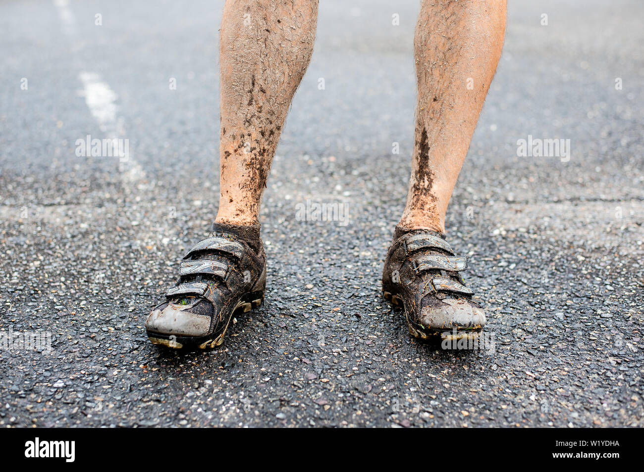 Detail der Männerbeine in Radfahren spikes nach Fahrt in nassem und schlammigem Gelände. Stockfoto