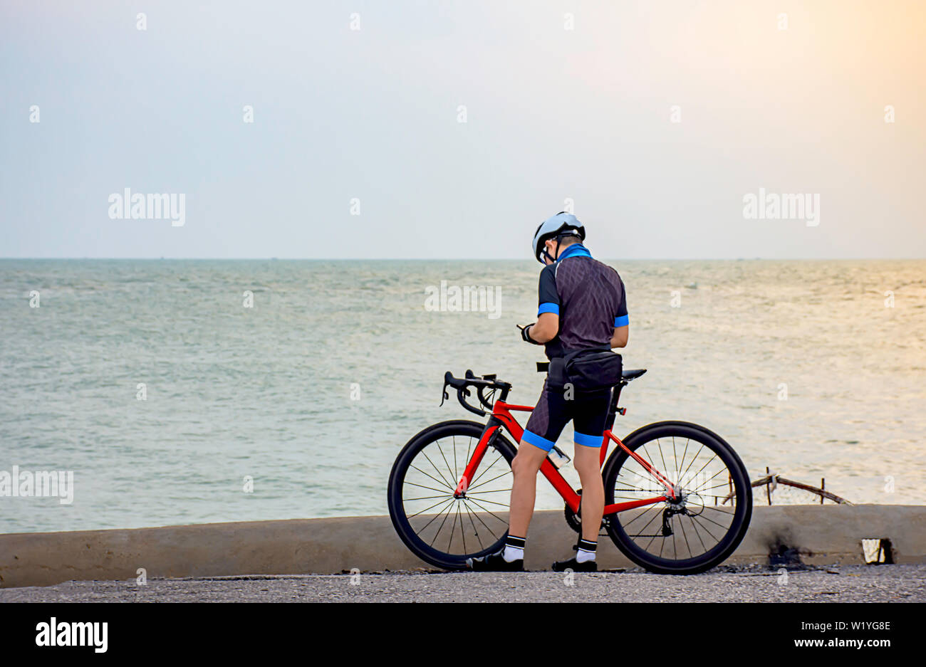 Mann und ein Fahrrad auf der Straße am Meer am Morgen geparkt. Stockfoto