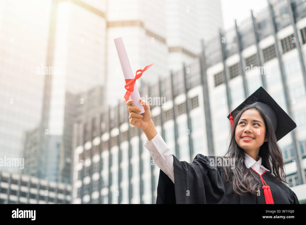 Frau in Kleid anheben Hand mit Erfolg Bachelor der Universität Stockfoto