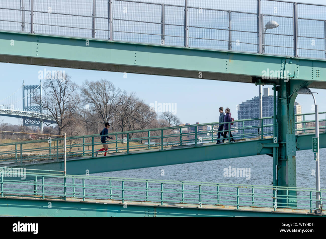 New York City, NY/USA, 19.03.2019: Menschen zu Fuß eine Jogging entlang der Struktur aus Stahl neben den East River, die Triboro Bridge im Hintergrund Stockfoto
