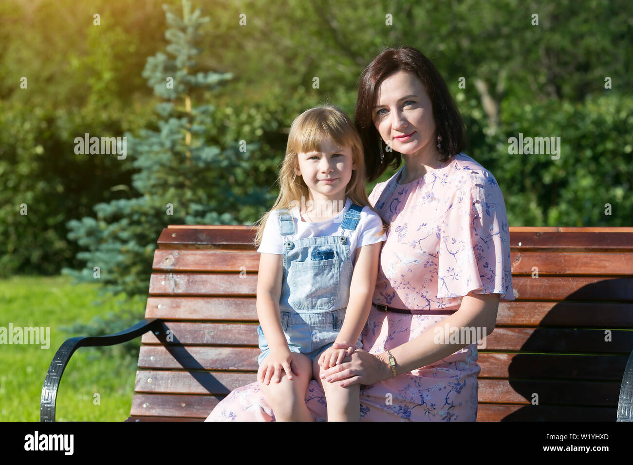 Junge Frau mit einem kleinen Mädchen auf einer Bank in einem Jahre Park Stockfoto