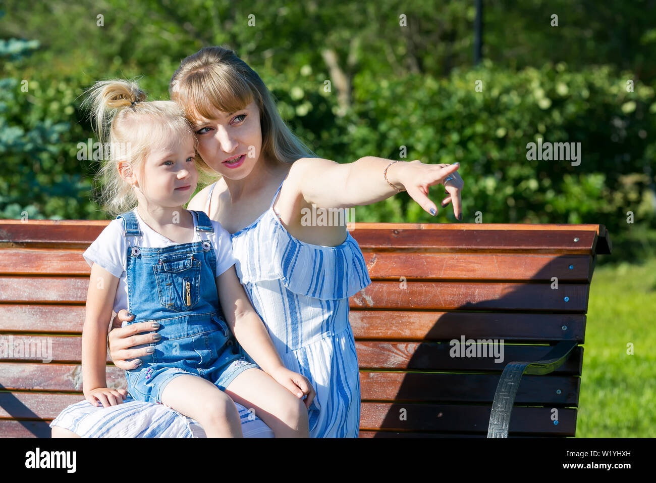 Junge Frau mit einem kleinen Mädchen auf einer Bank in einem Jahr Park. Stockfoto