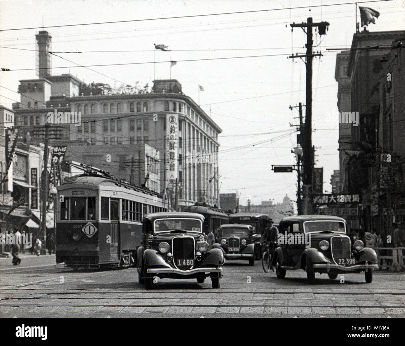 [1930er Jahre Japan - Nihonbashi, Tokyo] - Autos und Straßenbahnen auf Chuodori in Nihonbashi im Mai 1934 (Showa 9). Der Fotograf machte dieses Foto von der Kreuzung der Chuodori und Eitai-dori. Das Gebäude auf der Rückseite des Hotels ist Takashimaya Kaufhaus. 20. Jahrhundert vintage Glas schieben. Stockfoto