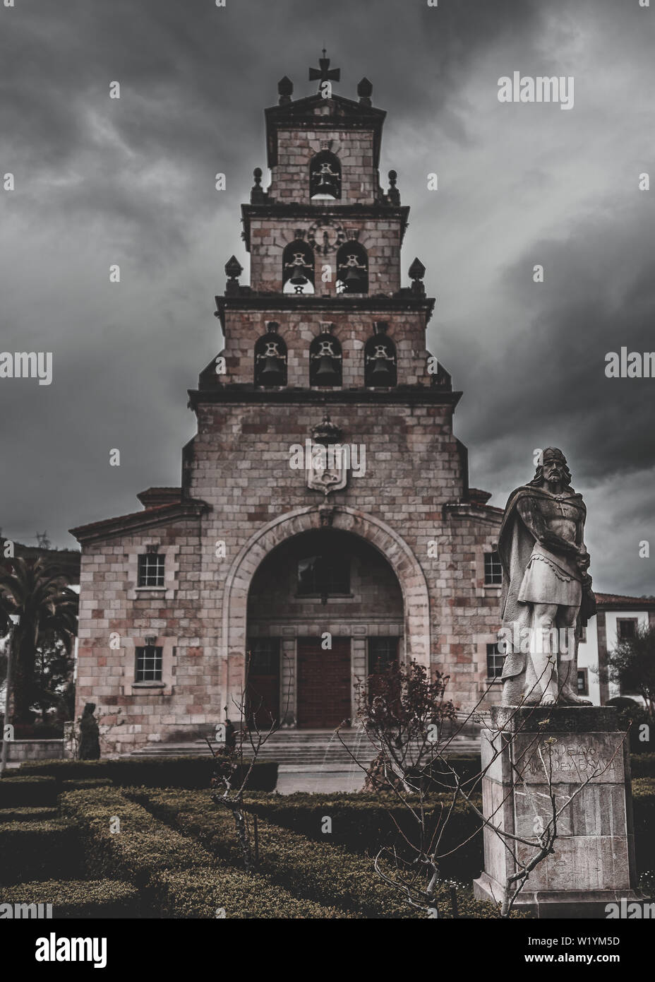 Cangas de Onis Kirche mit Statue von Don Pelayo im Vordergrund ein kaltes Grauen Tag. Stockfoto