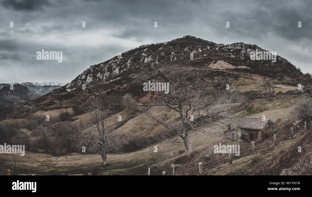 Asturische Bergpanorama im Naturpark Redes mit kleinen Haus und Bäume im Vordergrund hinter Zäunen und im Hintergrund die Berge. Stockfoto Asturische Bergpanorama im Naturpark Redes mit kleinen Haus und Bäume im Vordergrund hinter Zäunen und im Hintergrund die Berge. Stockfoto