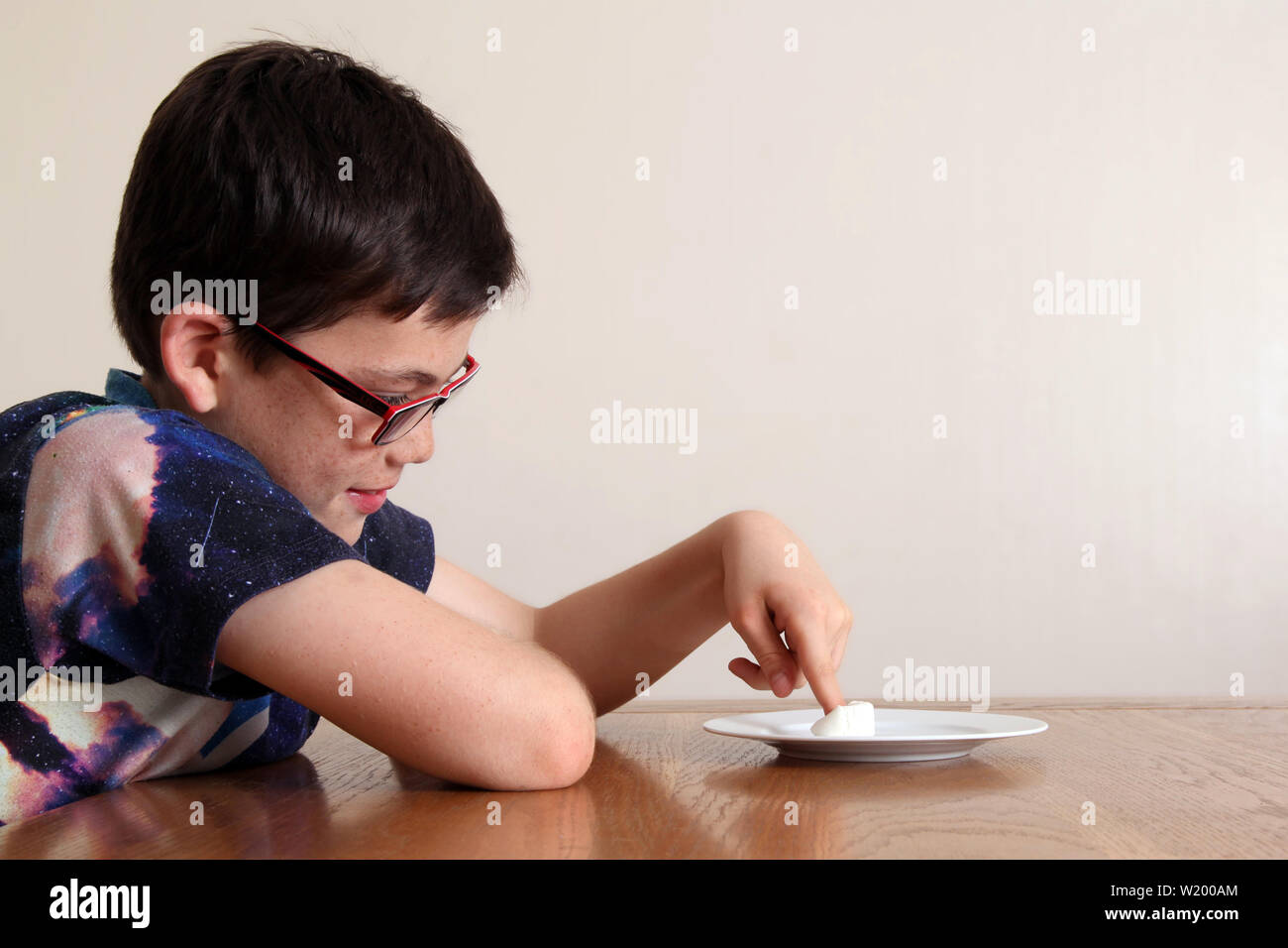 Die Marshmallow Experiment - Kind an einem Tisch sitzen, geduldig auf eine einzige Marshmallow, die eng vor das Gesicht des Kindes gelegt wird Stockfoto