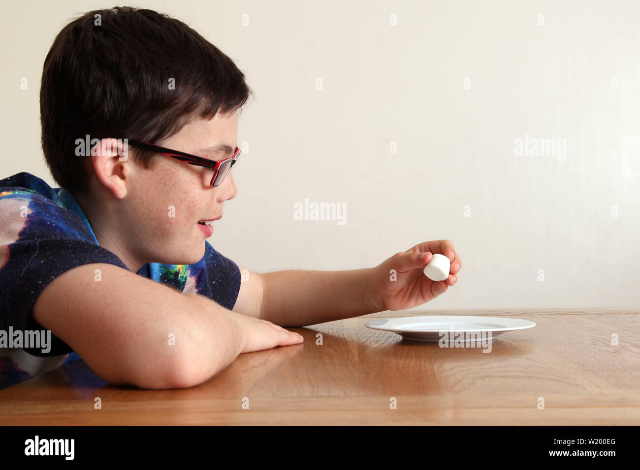 Die Marshmallow Experiment - Kind an einem Tisch sitzen, geduldig auf eine einzige Marshmallow, die eng vor das Gesicht des Kindes gelegt wird Stockfoto